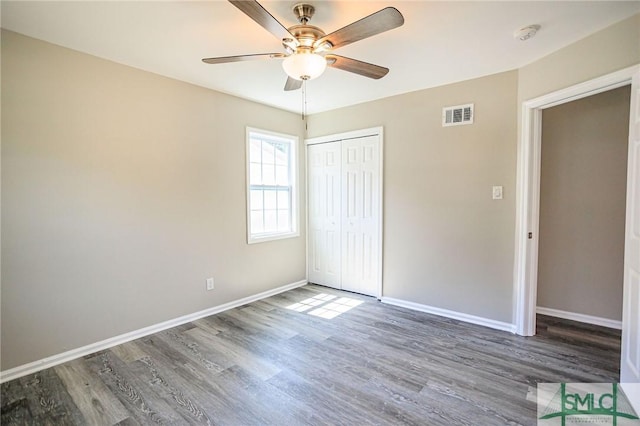 unfurnished bedroom with ceiling fan, dark hardwood / wood-style floors, and a closet