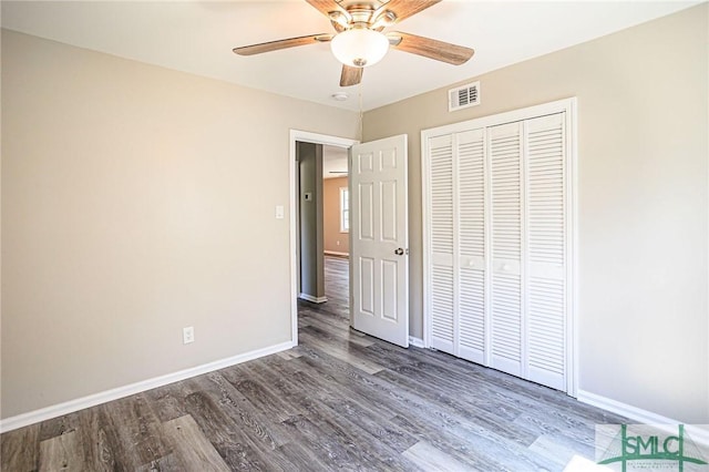 unfurnished bedroom featuring ceiling fan, dark hardwood / wood-style floors, and a closet