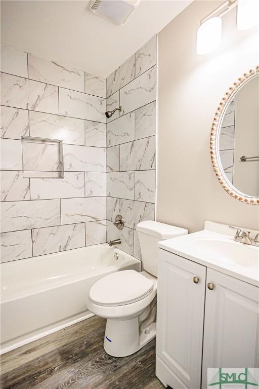 full bathroom with tiled shower / bath, wood-type flooring, toilet, and vanity