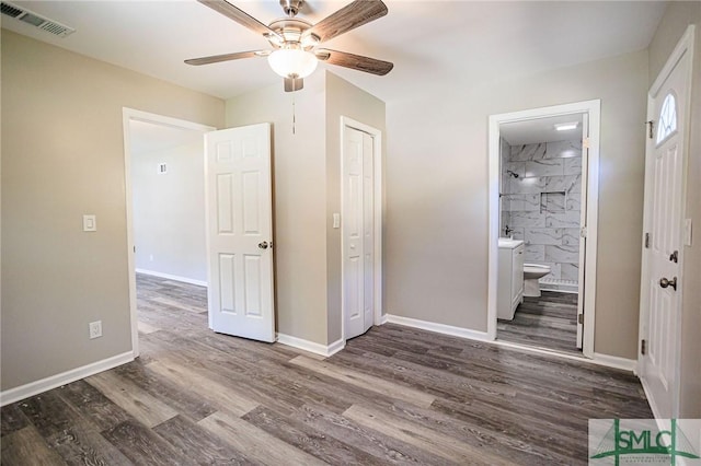 unfurnished bedroom with dark wood-type flooring, ceiling fan, ensuite bathroom, and a closet