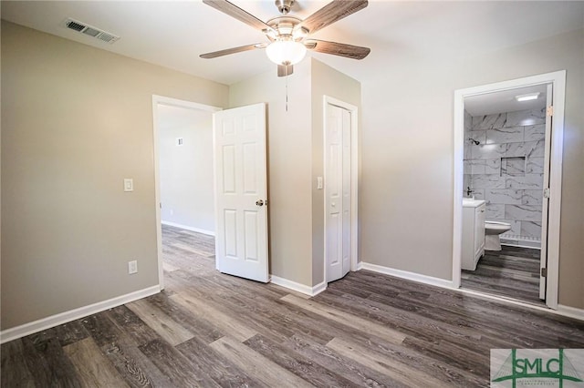 unfurnished bedroom featuring ensuite bathroom, ceiling fan, dark hardwood / wood-style flooring, and a closet