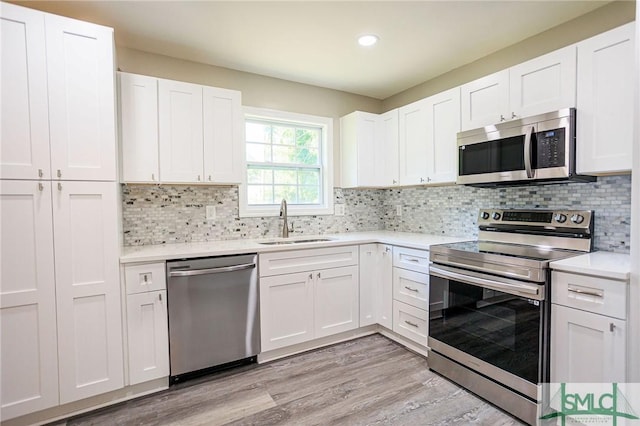 kitchen with white cabinetry, appliances with stainless steel finishes, light hardwood / wood-style floors, and sink