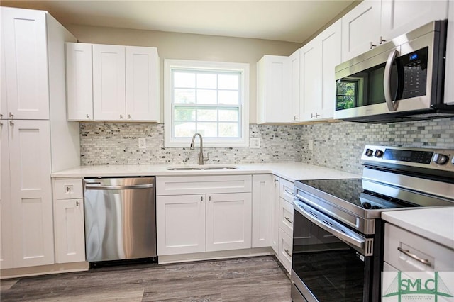 kitchen with sink, dark wood-type flooring, white cabinetry, stainless steel appliances, and decorative backsplash