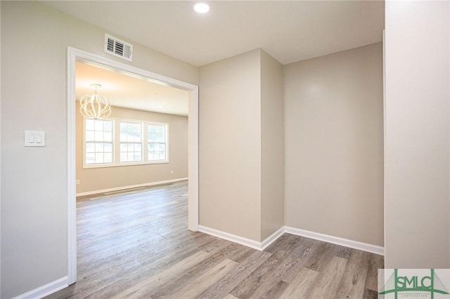 spare room with light hardwood / wood-style floors and a notable chandelier