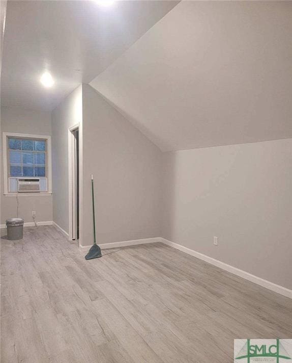 bonus room featuring cooling unit, light hardwood / wood-style flooring, and vaulted ceiling