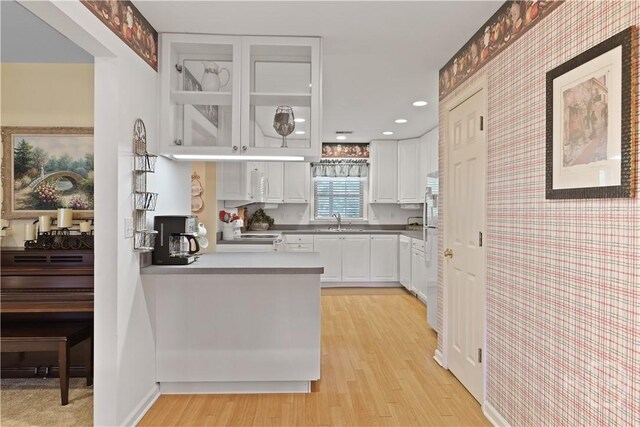 1280 Little Mccall Rd, Guyton, GA 31312 - kitchen featuring wallpapered walls, a sink, white cabinetry, light wood-style floors, and glass insert cabinets