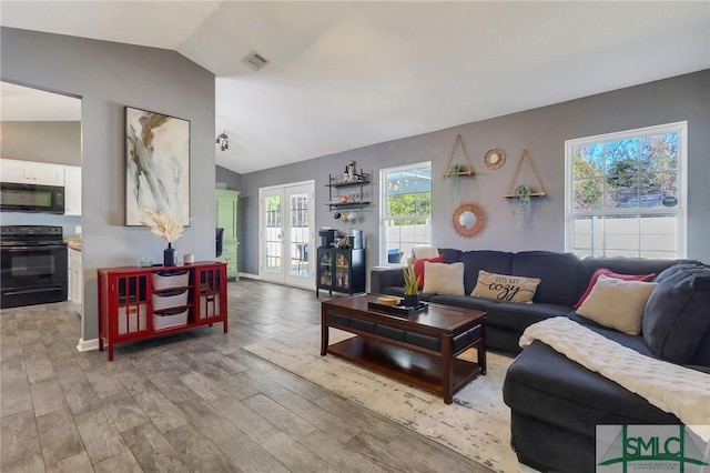 living room featuring french doors, vaulted ceiling, and light hardwood / wood-style flooring