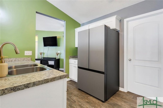 kitchen with dark hardwood / wood-style floors, lofted ceiling, sink, white cabinets, and stainless steel fridge