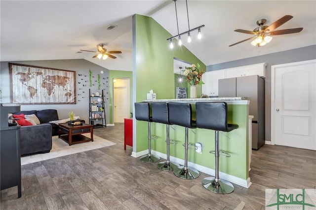 kitchen with a breakfast bar, decorative light fixtures, vaulted ceiling, kitchen peninsula, and white cabinets