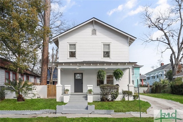 view of front of house with a porch, fence, and a front yard