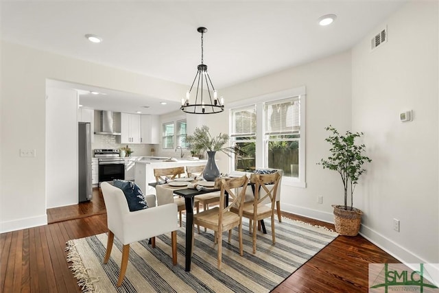 dining room featuring dark wood-type flooring, sink, and an inviting chandelier