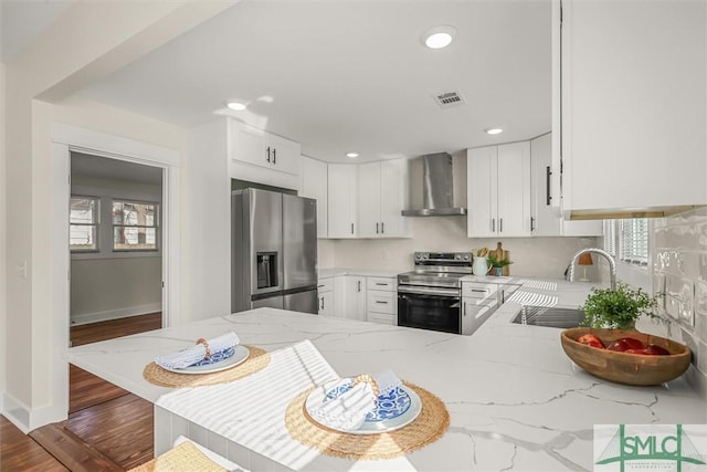 kitchen featuring appliances with stainless steel finishes, white cabinetry, sink, kitchen peninsula, and wall chimney exhaust hood