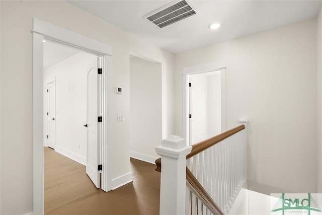 corridor with baseboards, visible vents, recessed lighting, an upstairs landing, and wood finished floors