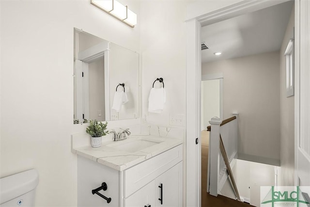 half bath featuring visible vents, vanity, and toilet