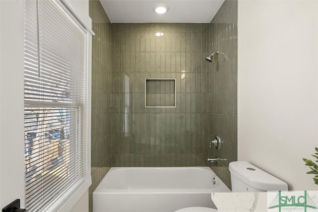 bathroom with tiled shower / bath combo and toilet