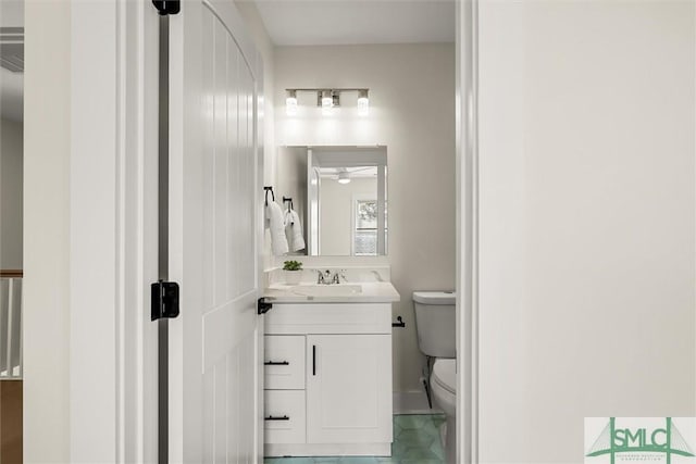 half bathroom featuring tile patterned flooring, baseboards, toilet, and vanity