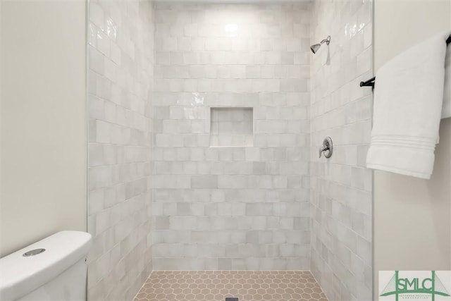 bathroom featuring a tile shower and toilet