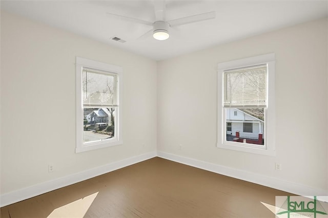 spare room featuring dark wood-style floors, baseboards, ceiling fan, and visible vents