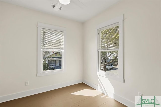 spare room featuring wood finished floors, visible vents, and baseboards