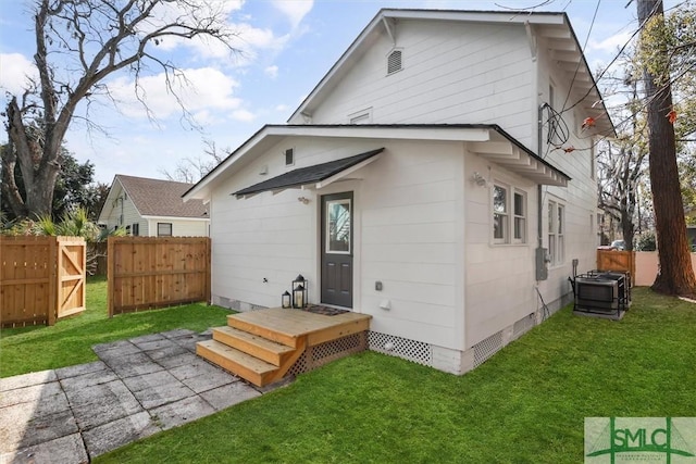 back of house featuring central AC unit and a lawn