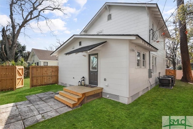 rear view of property with a lawn, crawl space, and fence