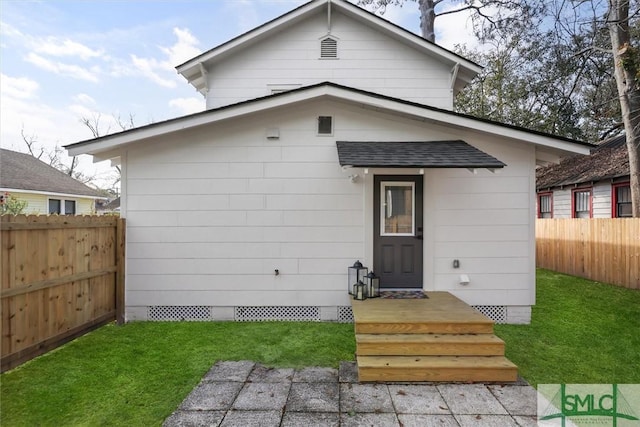 back of house featuring a yard, a shingled roof, and fence