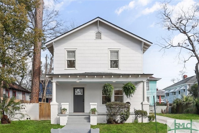 view of front of home with a front lawn, fence, and covered porch