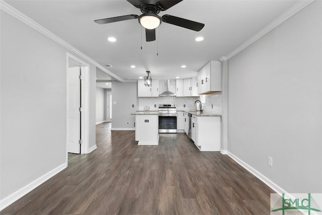 kitchen with wall chimney exhaust hood, crown molding, a kitchen island, stainless steel appliances, and white cabinets