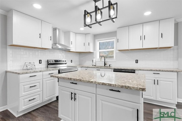 kitchen with pendant lighting, wall chimney range hood, white cabinets, and electric stove