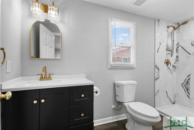 bathroom featuring vanity, wood-type flooring, tiled shower, and toilet