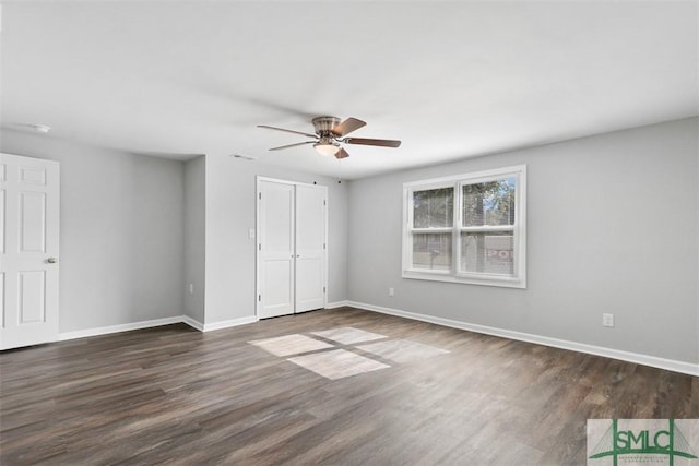 unfurnished bedroom with a closet, dark hardwood / wood-style floors, and ceiling fan