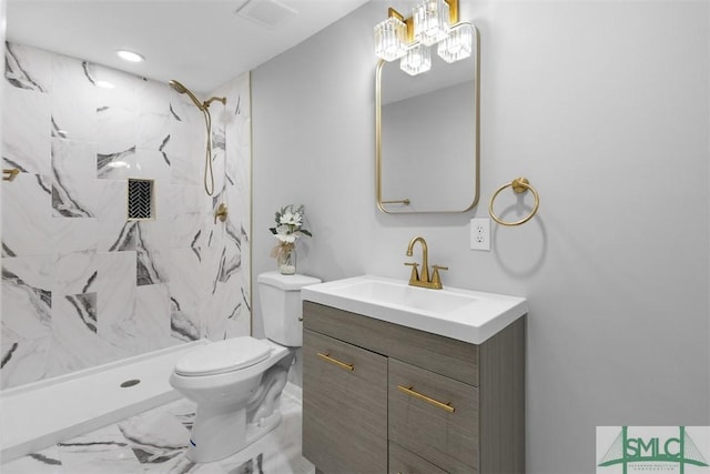 bathroom with vanity, tiled shower, and toilet