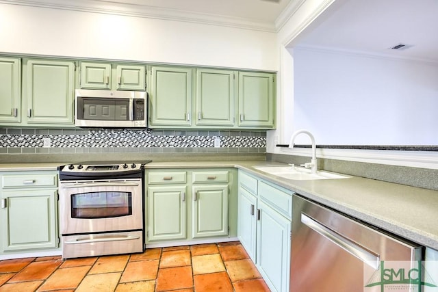 kitchen featuring sink, crown molding, green cabinetry, stainless steel appliances, and decorative backsplash