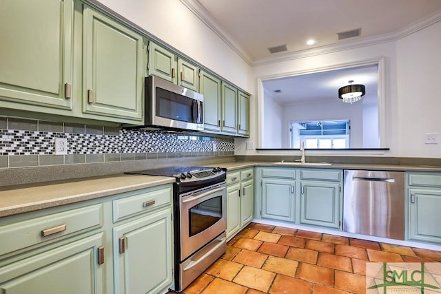 kitchen featuring sink, crown molding, appliances with stainless steel finishes, green cabinets, and decorative backsplash