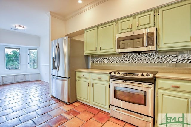 kitchen with ornamental molding, appliances with stainless steel finishes, green cabinets, and backsplash