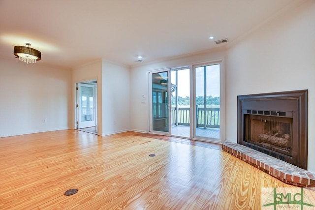 unfurnished living room featuring hardwood / wood-style flooring, crown molding, and a brick fireplace