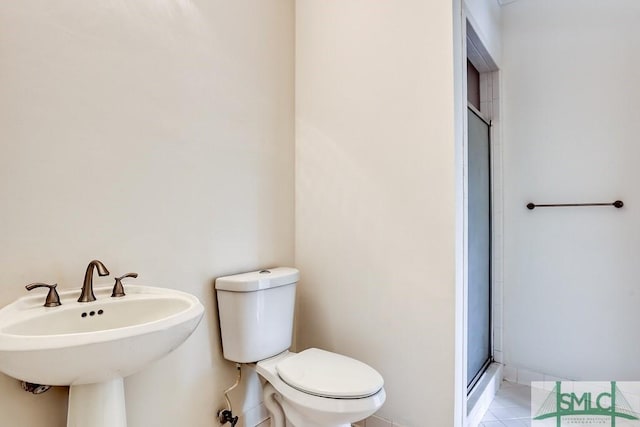 bathroom with a shower with door, sink, tile patterned flooring, and toilet