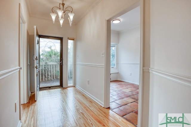 foyer with crown molding, a wealth of natural light, a chandelier, and light hardwood / wood-style flooring