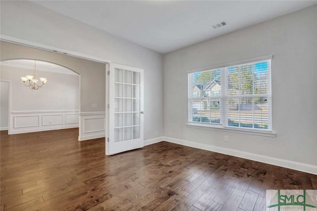 spare room with dark wood-type flooring and a notable chandelier