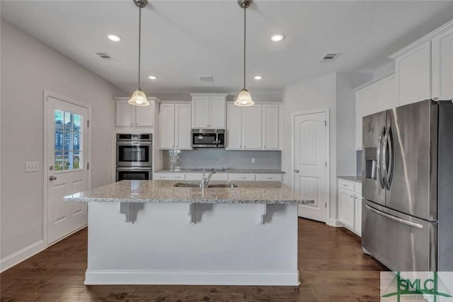 kitchen featuring white cabinetry, appliances with stainless steel finishes, a kitchen island with sink, and decorative light fixtures