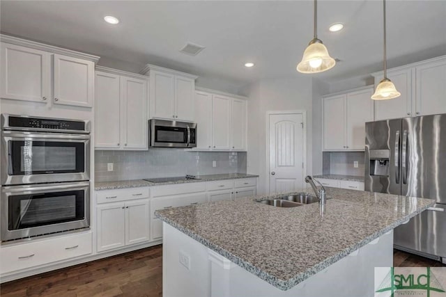 kitchen featuring sink, appliances with stainless steel finishes, white cabinetry, hanging light fixtures, and an island with sink