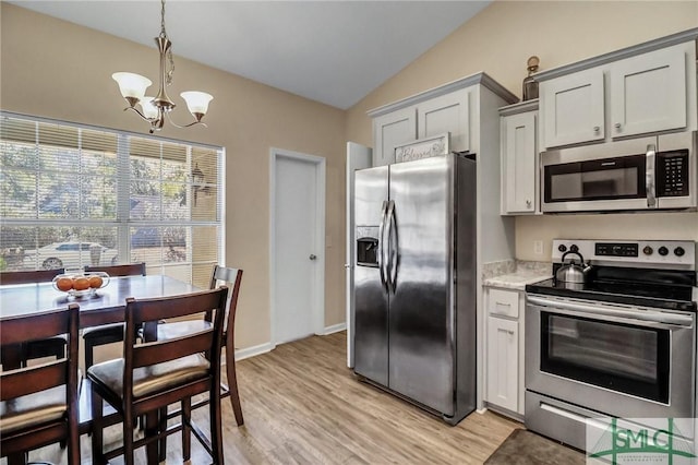 kitchen featuring light hardwood / wood-style flooring, appliances with stainless steel finishes, an inviting chandelier, decorative light fixtures, and vaulted ceiling