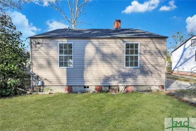 view of property exterior with a yard, crawl space, a chimney, and fence