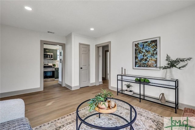 living room featuring recessed lighting, visible vents, baseboards, and wood finished floors