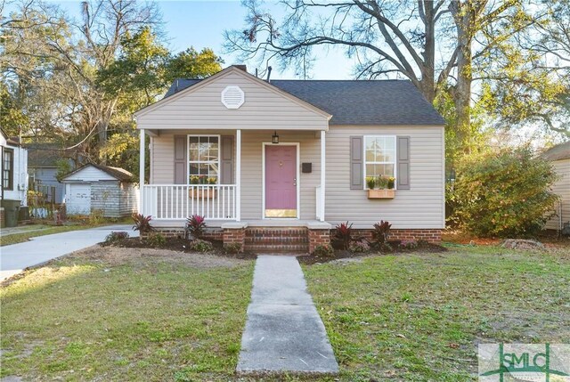 bungalow-style house featuring a shingled roof, a porch, and a front yard