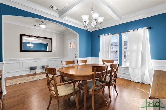 dining space featuring coffered ceiling, hardwood / wood-style flooring, ornamental molding, a notable chandelier, and beamed ceiling