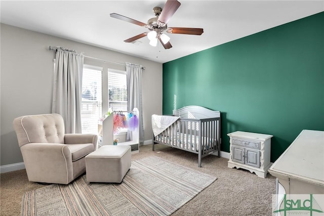 carpeted bedroom with ceiling fan and a crib