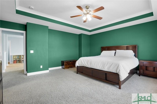 carpeted bedroom featuring a raised ceiling and ceiling fan