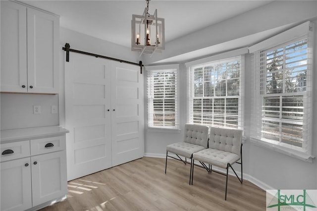 living area with plenty of natural light, light hardwood / wood-style floors, and a barn door