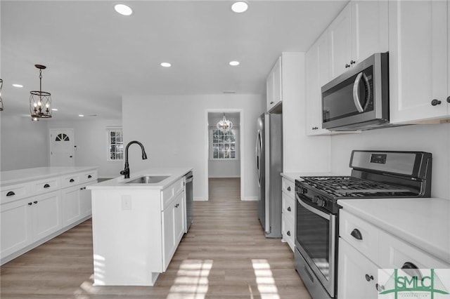 kitchen featuring stainless steel appliances, sink, a center island with sink, and white cabinets